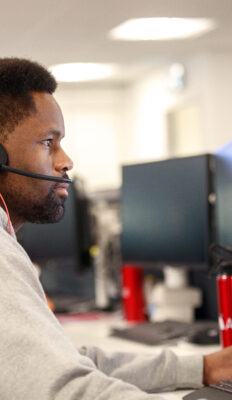 An Advanced tech support team member working on a computer wearing a headset
